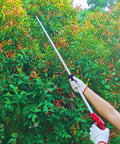 Person using a 4 Foot Aluminum Pole Pruner With Long Reach Pruning Shears Cut And Hold Garden Clippers on high branches.