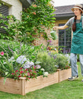 Person watering plants in Dual Section Divisible Wooden Raised Garden Bed 8 By 2 Feet Elevated Planter Box, backyard setting