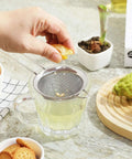 Hand squeezing lemon over Ultra Fine Mesh Strainer With Handle Stainless Steel Kitchen Sieve 3.35 Inch Small Filter for drinks