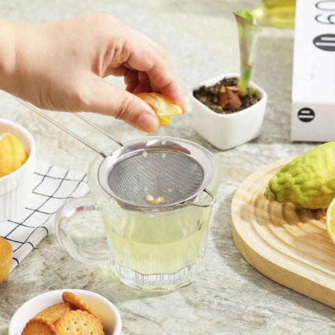 Hand squeezing lemon over Ultra Fine Mesh Strainer With Handle Stainless Steel Kitchen Sieve 3.35 Inch Small Filter for drinks