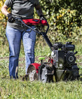 Person operating Pioneer Dual Direction Rear Tine Tiller with counter rotating and standard tines on grass field