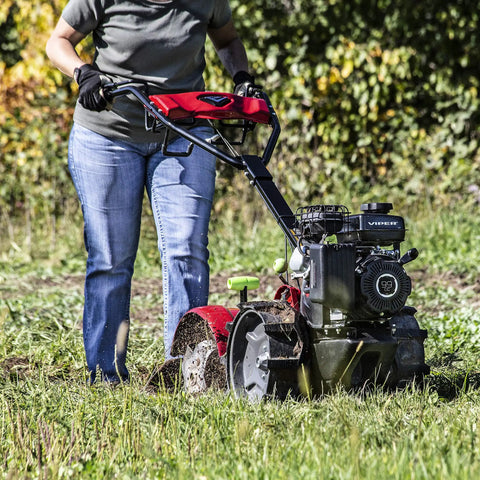 Person operating Pioneer Dual Direction Rear Tine Tiller with counter rotating and standard tines on grass field
