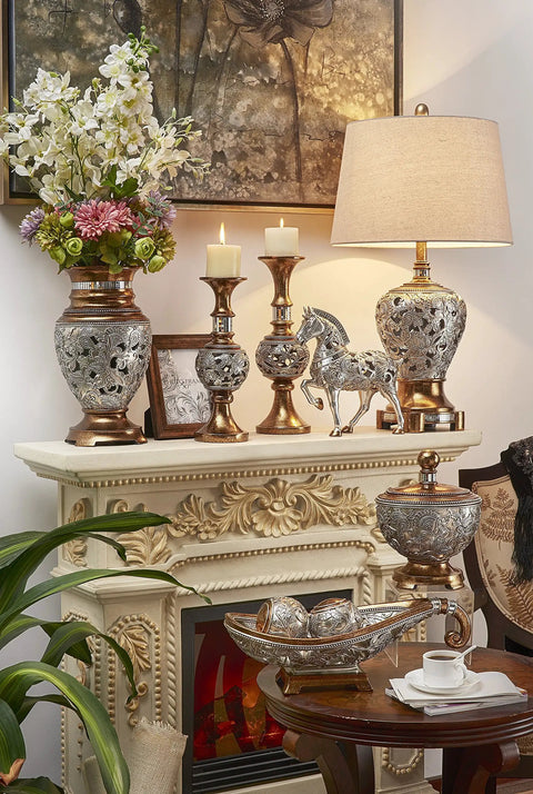 Langi Table Lamp With Mirrored Tile Neck Bronze Base With Silver Leaf Floral Accents Beige Drum Shade On Mantel