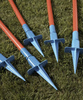 Close-up of Lightweight Dog Agility Slalom Kit stakes with red poles and blue bases on grass for backyard training and fun