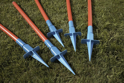 Close-up of Lightweight Dog Agility Slalom Kit stakes with red poles and blue bases on grass for backyard training and fun