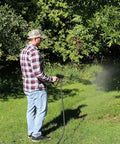 Man using Pistol Grip Deluxe Sprayer For Lawn Care Greenhouse Roof Spraying With Adjustable Brass Nozzle From Mist To Straight Stream 350 Psi 6 Gpm With Trigger Lock For Safety And Easy Use on trees in a garden.