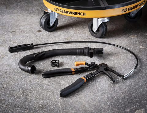 Cable Hose Clamp Pliers For Hard To Reach Clamps with snaking cable on garage floor, automotive tool visible