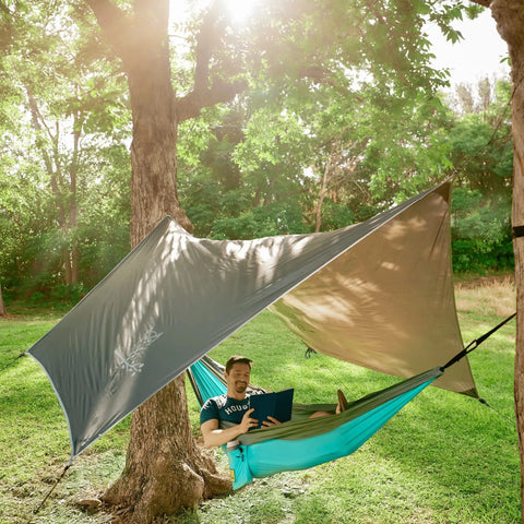 Man relaxing in hammock under Waterproof Hammock Rain Fly Tarp With Stakes And Carry Bag For Backpacking Ultralight Camping Shelter Ripstop Nylon