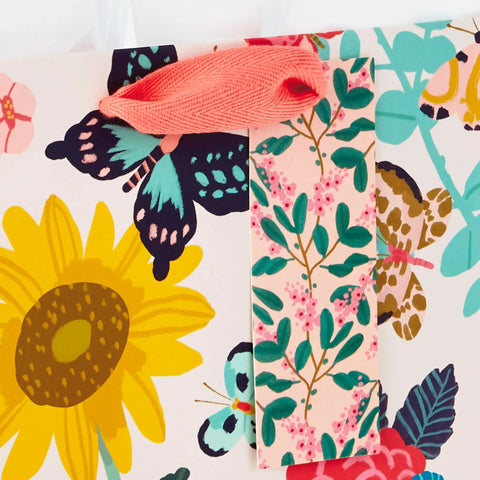 Nine Inch Medium Gift Bag With Tissue Paper Bright Flower Designs For Valentine Day Easter Birthdays Bridal Showers Weddings Baby Showers And Mothers Day A Cute Floral Gift Bag For Any Special Occasion showing floral and butterfly print with pink tag and handle