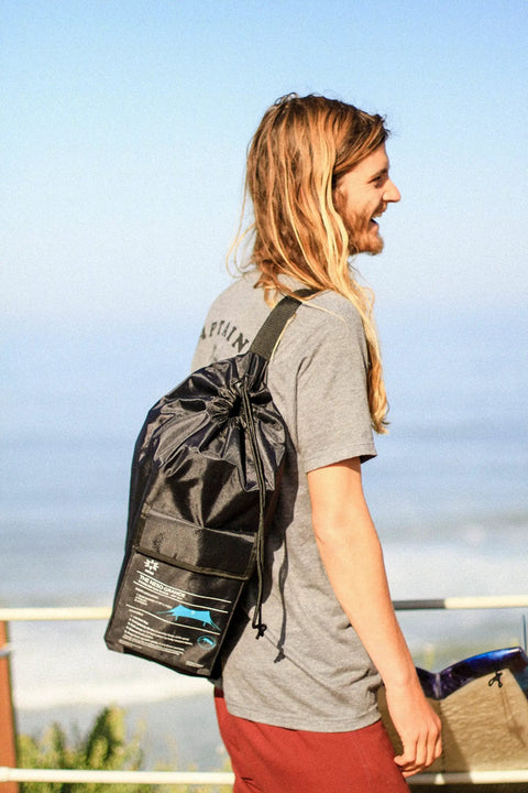 Man carrying Grande Portable Beach Tent Sun Shelter bag, showcasing compact storage, ideal for beach outings.