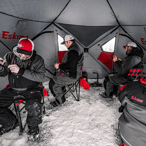 Three anglers inside Heavy Duty Pop Up Insulated Ice Fishing Shelter With Knockout Spacious Fishin Spot For Five To Seven Crews Quick Roll Setup Trip Proof Door Wide Flared Bottom Red Black 94 Square Feet.