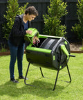 Person using 65 Gallon Dual Chamber Outdoor Compost Tumbler For Food Waste And Yard Waste Tough As Nails Heavy Duty Spill Proof Large Opening Bin For Your Kitchen Garden And Homestead in garden