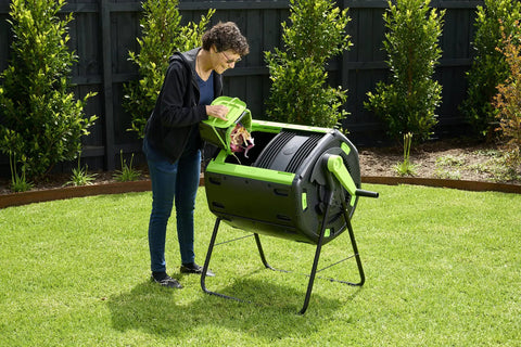 Person using 65 Gallon Dual Chamber Outdoor Compost Tumbler For Food Waste And Yard Waste Tough As Nails Heavy Duty Spill Proof Large Opening Bin For Your Kitchen Garden And Homestead in garden