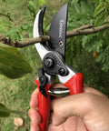 Hand using 8 Inch Bypass Pruning Shears For Garden And Bonsai Heavy Duty Sharp Pruner With Drop Forged Steel cutting a branch