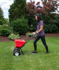 Person using Big 80lb Capacity Broadcast Spreader For Lawns And Seeds With Rustproof Poly Hopper Pre Assembled Adjustable Drop