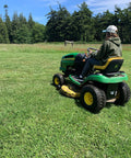 Person using a green riding mower with Tubeless Pneumatic Tire and Wheel Assembly 20x8.00-8 Turf Traction Tread For Riding Mowers