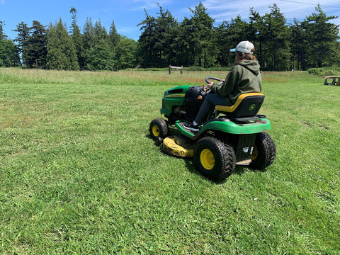 Person using a green riding mower with Tubeless Pneumatic Tire and Wheel Assembly 20x8.00-8 Turf Traction Tread For Riding Mowers