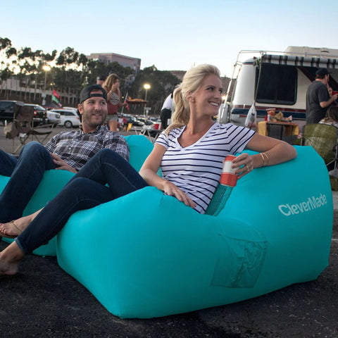 People sitting on Inflatable Lounger Air Chair Lightweight Self Inflating Beach Chair with pockets, teal color, in outdoor setting.