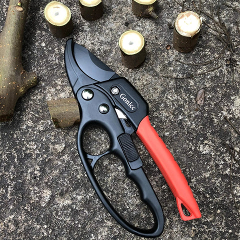 Badass Heavy Duty Anvil Pruning Shears 8 Inch Blade Ratchet Action Pruner on stone surface with cut branches nearby.