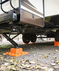 Stop N Chock 2 Pack For No Fuss Safe Parking And Easy Stabilization installed under RV, showing orange porous PLA chocks