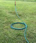 Heavy Duty Flexogen Three Quarters Inch By Fifty Foot Garden Hose With Eight Layer Construction And Five Hundred Psi Burst Strength, Kink Resistant, Ergonomic Brass Couplings, Pro Grade Built To Last coiled on grass beside outdoor faucet.