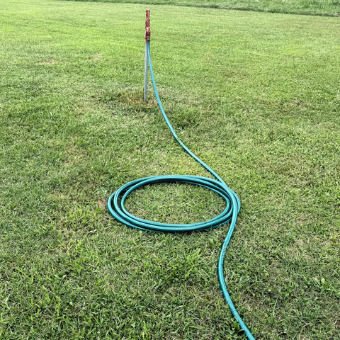 Heavy Duty Flexogen Three Quarters Inch By Fifty Foot Garden Hose With Eight Layer Construction And Five Hundred Psi Burst Strength, Kink Resistant, Ergonomic Brass Couplings, Pro Grade Built To Last coiled on grass beside outdoor faucet.