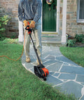 Person using 2 In 1 Electric Lawn Edger And Trencher With 12 Amp Corded Power, 7.5 Inch Cutting Width, along a sidewalk edge