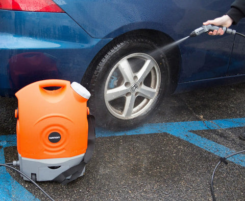 On The Go Portable Spray Washer With Built In Water Tank, orange unit with integrated wheels, cleaning car tire, not high pressure