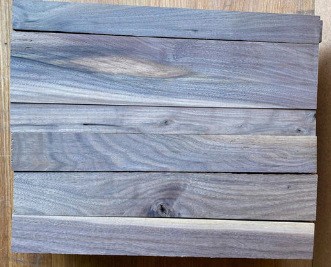 Scrap Walnut Box Of 3/4 Inch Thick Boards In A 17 By 14 By 5 Inch Crate, Leftover Walnut With Rough Edges And Knots, Perfect For DIY Woodworking, Crafts, Hobby Projects, And Reclaimed Lumber arranged on floor