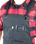 Person wearing Deluxe Waxed Canvas Tool Apron For Men And Women With Removable Padded Straps And Dual Hammer Loops and front pocket detail