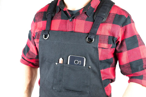 Person wearing Deluxe Waxed Canvas Tool Apron For Men And Women With Removable Padded Straps And Dual Hammer Loops and front pocket detail