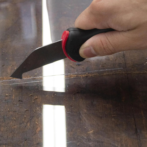Allway Hardened Steel Plastic Sheet Cutter With Ergonomic Design For Easy Scribing Snapping Fiberglass And Vinyl Panels Home Shop Tool Heavy Duty Handle Comfort Grip Professional Grade Cutting Instrument cutting through plastic sheet on a wooden surface.