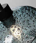 Close-up of hand blown glass pendant light with grey blue and matte black finish, modern farmhouse style texture detail.
