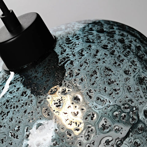 Close-up of hand blown glass pendant light with grey blue and matte black finish, modern farmhouse style texture detail.