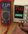 MM525 True RMS 6000 Count Digital Multimeter With NIST Calibration Certificate next to power supply showing measurements