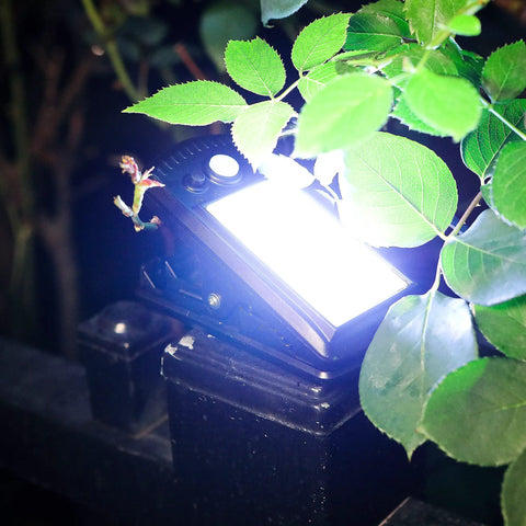 4 Pack Solar Motion Sensor Clip Lights With 40 LEDs illuminating a garden fence at night, surrounded by leaves.