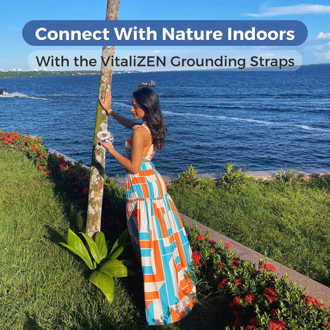 Woman using VitaliZEN grounding straps by a waterfront, showcasing EMF Shield Grounding Kit With 2 Cords And 2 Wrist Straps For Home Or Office.