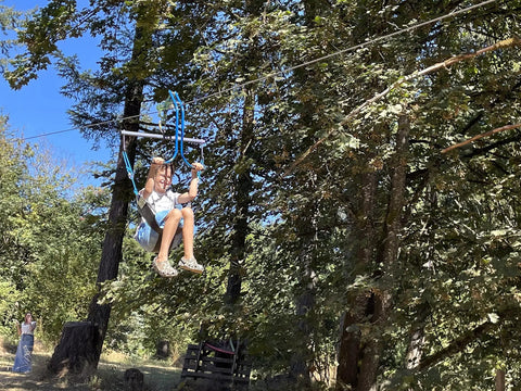 Backyard Zipline Seat For Trolley Use Heavy Duty Black Metal Swing Seat with woman using the zipline in a forest setting