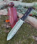Hori Hori Garden Knife With Leather Sheath And Handguard Pro Grade 440 Stainless Steel Blade lying on grass with sheath in background.