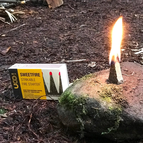 Sweetfire Biofuel Fire Starters For Camping, Backpacking, And Emergency Prep, Strikeable Tinder Tab lit on a rock outdoors