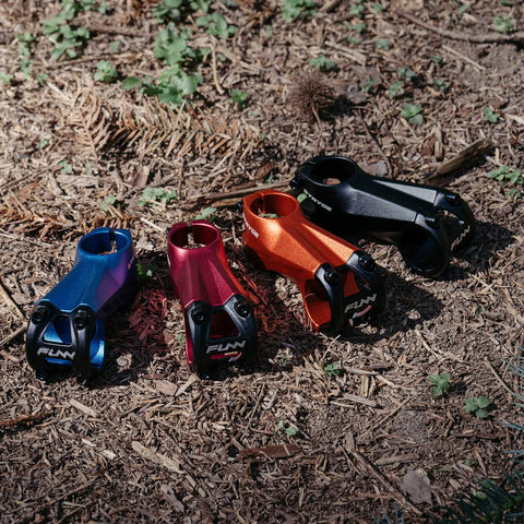 Four Stryge Drop Stems for 35mm Handlebars, -5 Degree Drop, 75mm Length, 35mm Bar Clamp in various colors on grass surface