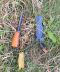 Ferro Rod Survival Kit With Flint And Steel Fire Starter And Whistle in grass, featuring paracord and upgraded striker.