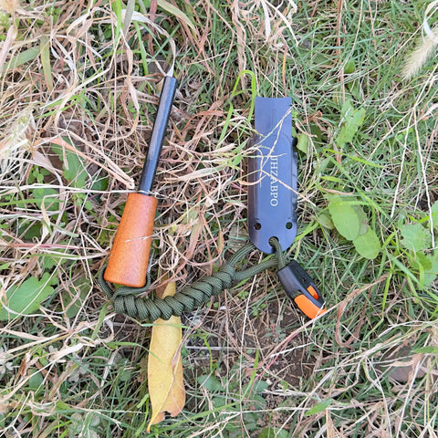 Ferro Rod Survival Kit With Flint And Steel Fire Starter And Whistle in grass, featuring paracord and upgraded striker.