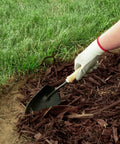 Gardener using a trowel to prepare ground for Killer 4 Inch No Dig Landscape Edging Kit With 75 Foot Black Plastic Edging Coil And 64 Spiral Anchoring Spikes