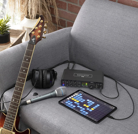 USB-C 6x4 Audio Interface With Pro-Grade Studio-Quality Sound And ESS Sabre32 DAC, 120 dB Dynamic Range on a sofa with guitar and tablet.