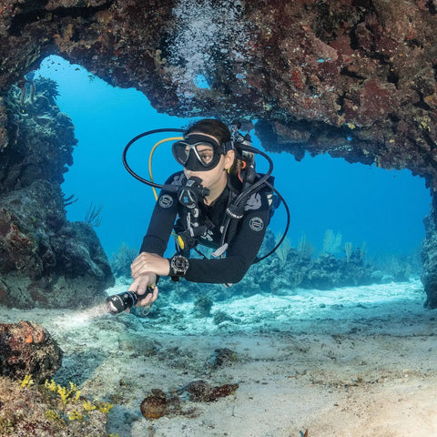 Diver using G3 Wrist Scuba Dive Computer With Bluetooth And Watch Style Color Display near underwater rock formations