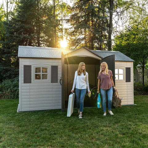 Two people exiting Desert Sand Outdoor Storage Shed 15x8 Ft Resin Backyard Tool Shed with lockable doors and UV-protected panels