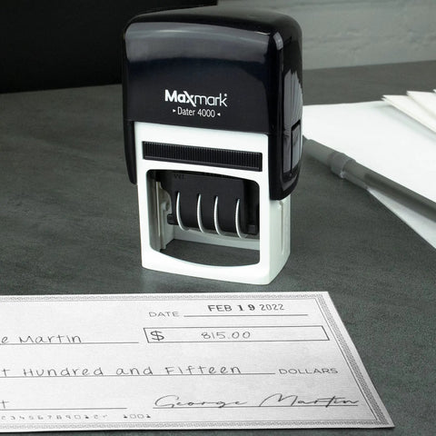 Built Tough Self Inking Date Stamp With Bright Red Ink And Big Bold Four Millimeter Dates on a desk next to a check.