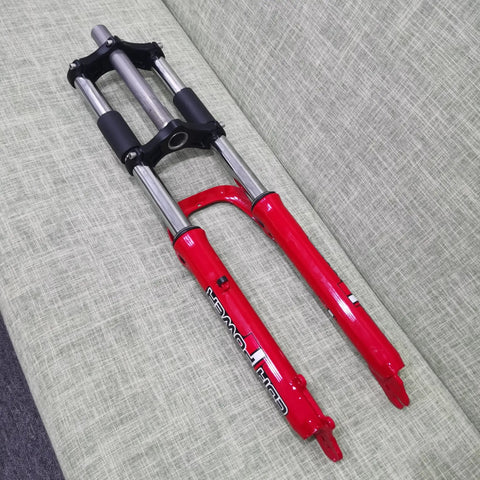 26 Inch Suspension Front Fork With One And One Eighth Inch Headset Disc Brake Ready Aluminum Triple Tree Red Travel 90 100mm 28.6mm Threadless Steerer 50mm Disc Mount Fits Mountain Bikes displayed on gray sofa