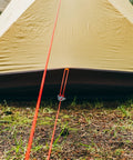 Paracord 175 Lightweight Visible Guyline For Tents And Tarps Reflective Orange 100 Ft Camping Cord shown securing a tent